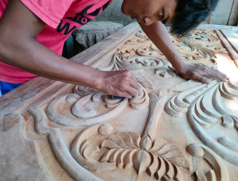 Artisan carving a wooden panel at Alipurduar